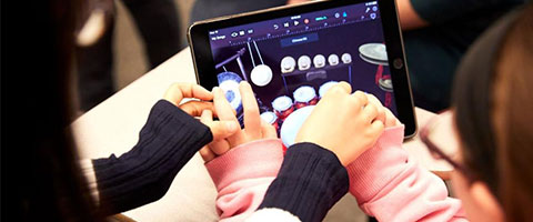 A music therapy student being guided to use a music app on a tablet