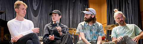 The members of Big Thief sitting on a stage answering student questions
