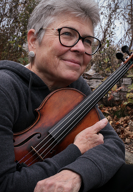 Judith Eissenberg headshot - holding violin and grinning