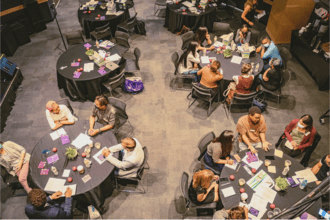 Picture from above of tables and people collaborating around it.