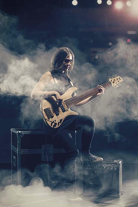 Ciara Moser playing bass in smoky stage setting