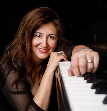 Professor Consuelo Candelaria-Barry resting on a piano keyboard