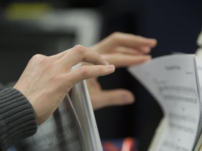 Hands leafing through sheet music