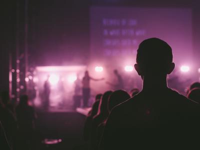 Silhouette of audience member backlit against a stage with purple lighting