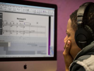 Young man pensively staring at a monitor displaying digital music production software