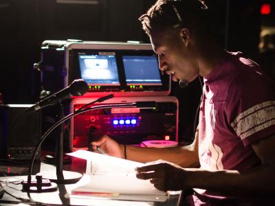 Man at a workstation with recording hardware and microphones