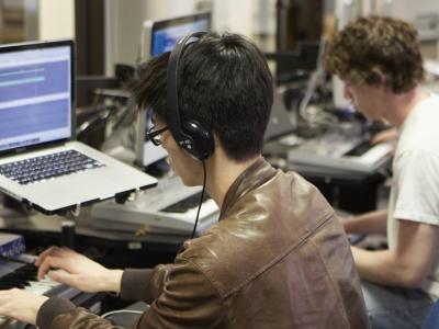 Young men in a studio working with electronic music hardware and software