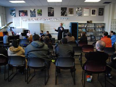 Man in a classroom introducing young musicians to an audience