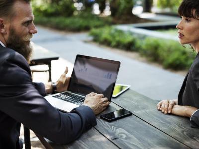 Two people in formal business attire having an outdoor meeting