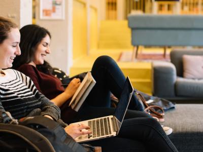 Two young women laughing on a couch together