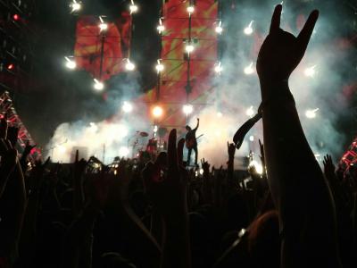 Silhouette of audience hands at a smoky and dramatically lit rock concert