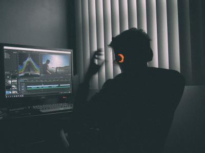 Silhouette of a person seated at a computer working on an audio and video project