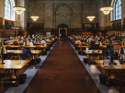 People reading and studying in a vast library with cathedral ceiling