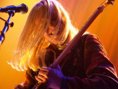 Woman playing guitar onstage with orange lights
