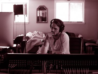 Man sitting in a room surrounded by digital music production equipment