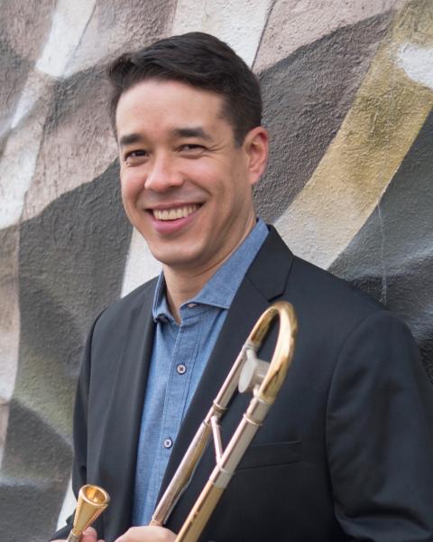 Professional headshot of John Yao holding trombone