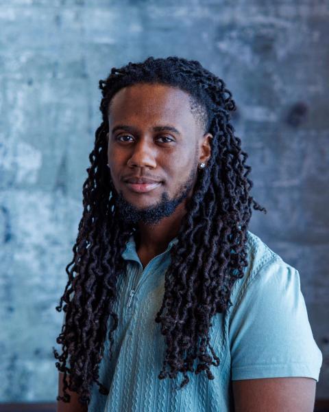 Drummer Dominic Glaude poses with light blue shirt on.