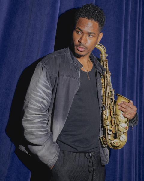 Saxophonist poses with saxophone.