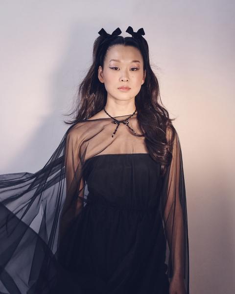 Singer-songwriter Adeline Um poses in all-black dress.