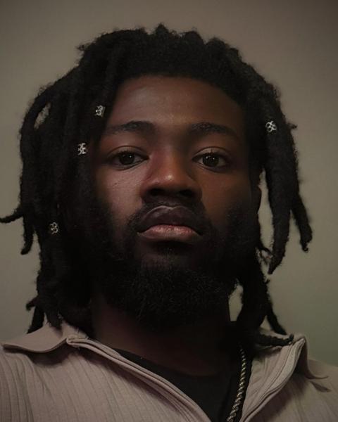 Diji Diallo poses on a tan backdrop