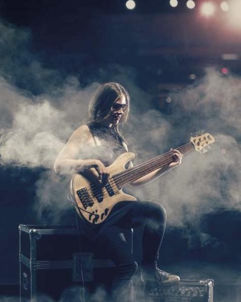 Ciara Moser playing bass in smoky stage setting