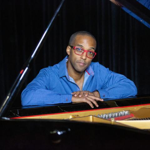 Pianist and composer Kevin Harris seated at a grand piano