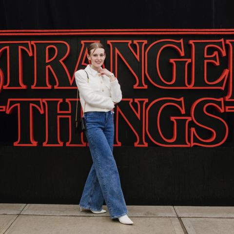 Lena Glikson standing in front of the Stranger Things logo 