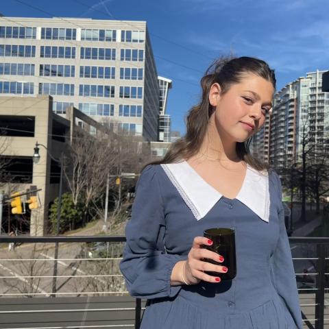 Girl, blue dress, sunny city behind her