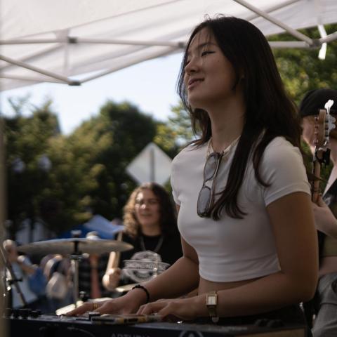 Sean Kim on stage with keyboard, wearing a white baby tee. 