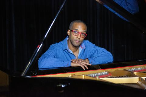 Pianist and composer Kevin Harris seated at a grand piano
