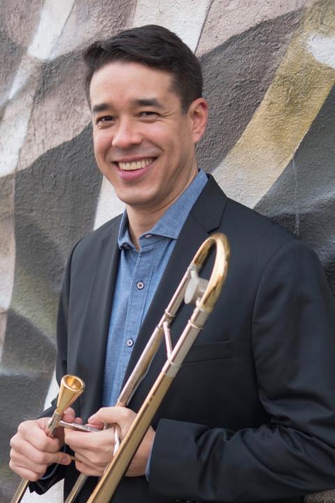 Professional headshot of John Yao holding trombone