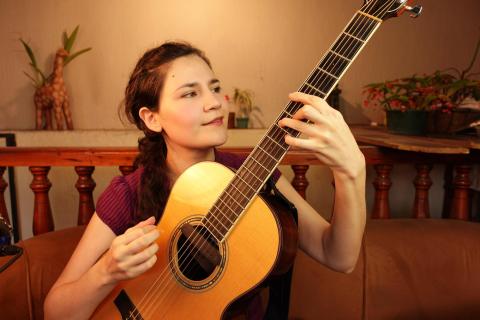 Mercedes Escobar playing an acoustic guitar