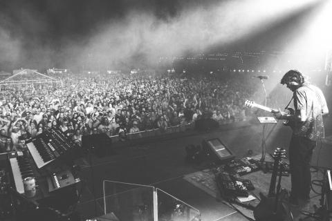 black and white photo of a guitarist playing at night in front of an outdoor concert audience