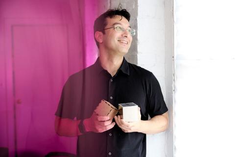 picture of akito van troyer holding two small custom-built musical cubes