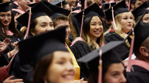 Students wearing their gaps and gowns at graduation, smiling.