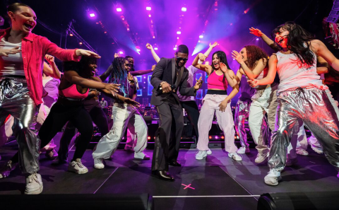 Usher dancing on stage amidst a crowd of people dancing excitedly.