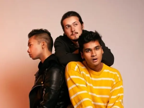 The members of Roy Juno seated together, two facing the camera while one looks off to the side.