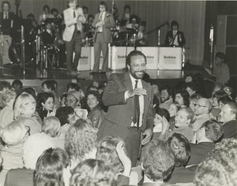 Quincy Jones standing amidst a seated crowd at Berklee commencement in 1983