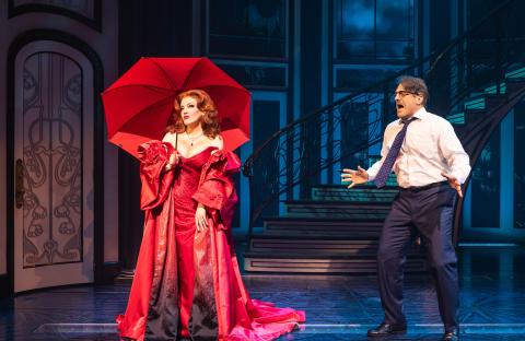 Jennifer Simard (in red dress and umbrella) and costar Christopher Sieber (in a jacket-less suit and tie) on stage in 'Death Becomes Her'