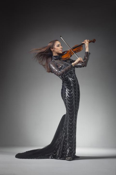 Anyango Yarbo-Davenport in dramatic long black dress playing the violin with wind blowing her long hair.