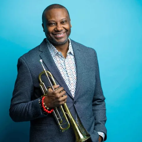 Sean Jones smiling holding trumpet in right hand
