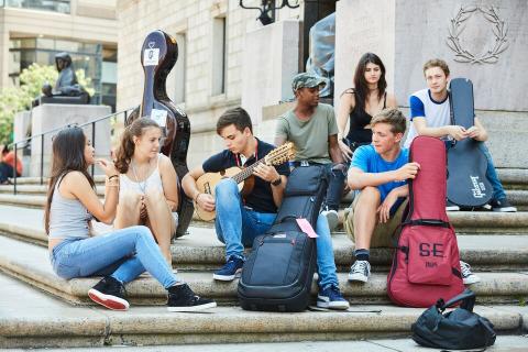 Student with instruments sitting on steps