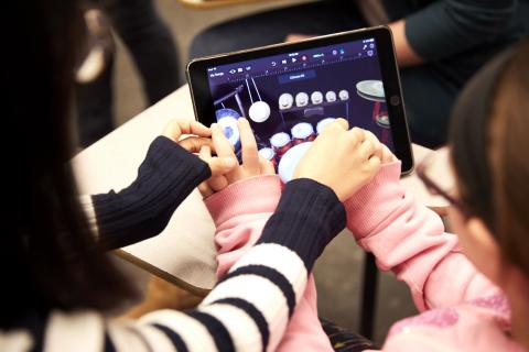 teacher teaching child to use iPad