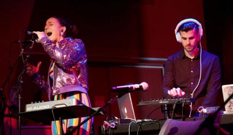 Woman singing and man performing music on a MIDI controller. 